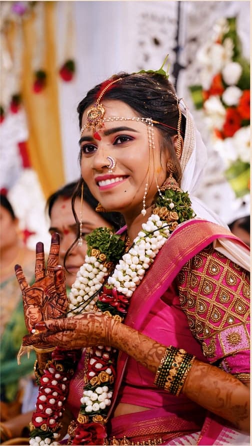 Close-up of a smiling bride with intricate mehndi on her hands and jasmine garlands around her neck