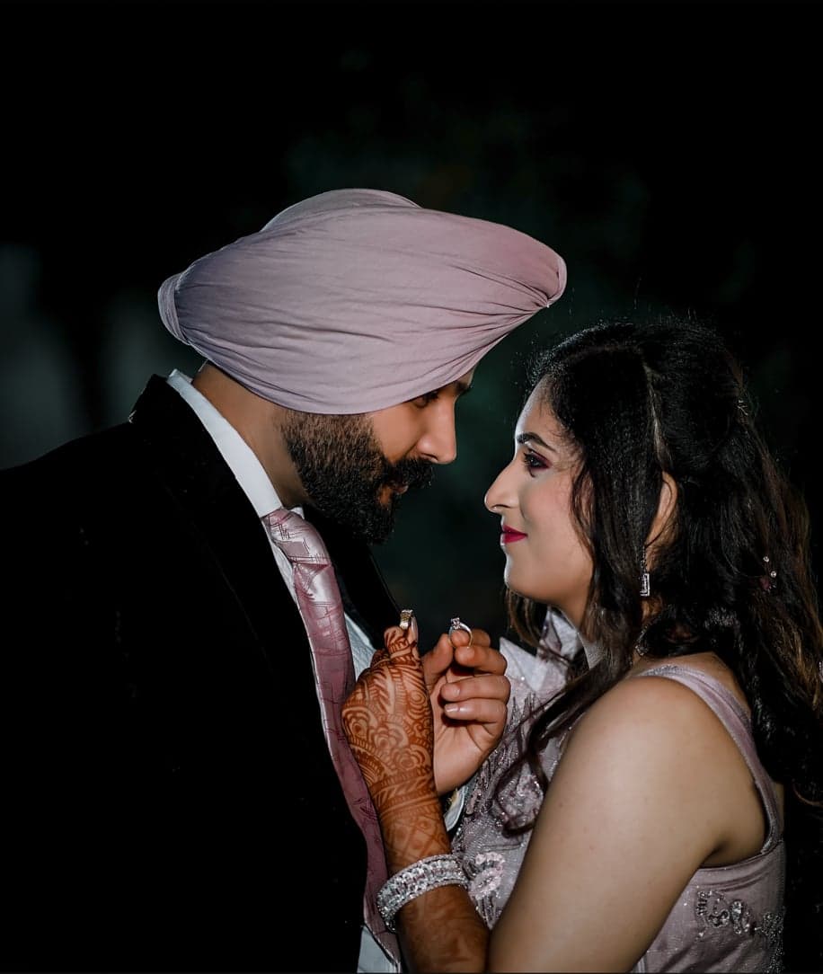 Groom in a lavender turban and his bride sharing a quiet, close look at night, showing off their rings